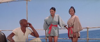 Movie still from “Krakatoa: East of Java” (1968), directed by Bernard L. Kowalski – Two women in robes standing on a pier; Medium shot, Low angle