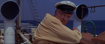 Movie still from “Krakatoa: East of Java” (1968), directed by Bernard L. Kowalski – An older man wearing a hat and a jacket on a boat; Medium shot, Low angle