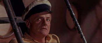 Movie still from “Krakatoa: East of Java” (1968), directed by Bernard L. Kowalski – An older man wearing a sailor's hat and holding a sword; Close Up shot, Low angle