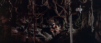 Movie still from “Krakatoa: East of Java” (1968), directed by Bernard L. Kowalski – A man sitting in a room filled with ropes; Wide shot, High angle