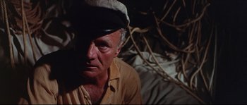 Movie still from “Krakatoa: East of Java” (1968), directed by Bernard L. Kowalski – An older man wearing a hat and a yellow shirt; Close Up shot, High angle
