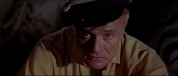 Movie still from “Krakatoa: East of Java” (1968), directed by Bernard L. Kowalski – An older man wearing a hat and a yellow shirt; Close Up shot, Low angle