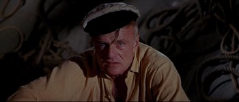 Movie still from “Krakatoa: East of Java” (1968), directed by Bernard L. Kowalski – An older man wearing a hat and a yellow shirt; Close Up shot, High angle