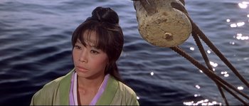 Movie still from “Krakatoa: East of Java” (1968), directed by Bernard L. Kowalski – A woman in a green and yellow kimono standing next to a body of water; Close Up shot, High angle