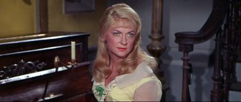 Movie still from “Krakatoa: East of Java” (1968), directed by Bernard L. Kowalski – A woman with long blonde hair wearing a yellow dress; Close Up shot, Over the shoulder angle
