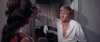 Movie still from “Krakatoa: East of Java” (1968), directed by Bernard L. Kowalski – A man in a white shirt is looking in the mirror; Medium shot, Over the shoulder angle