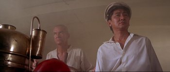 Movie still from “Krakatoa: East of Java” (1968), directed by Bernard L. Kowalski – Two men standing next to each other in front of a fire hydrant; Close Up shot, Low angle