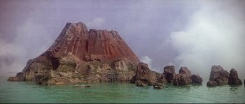 Movie still from “Krakatoa: East of Java” (1968), directed by Bernard L. Kowalski – A body of water surrounded by mountains and a cloudy sky; Extreme Wide shot, High angle