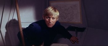 Movie still from “Krakatoa: East of Java” (1968), directed by Bernard L. Kowalski – A man with blonde hair sitting in a room; Close Up shot, High angle