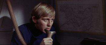 Movie still from “Krakatoa: East of Java” (1968), directed by Bernard L. Kowalski – A young man holding a metal cup in his mouth; Close Up shot, High angle