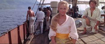 Movie still from “Krakatoa: East of Java” (1968), directed by Bernard L. Kowalski – A woman standing on the deck of a boat; Medium shot, Low angle