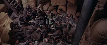 Movie still from “Krakatoa: East of Java” (1968), directed by Bernard L. Kowalski – A group of men sitting on top of rocks; Wide shot, Overhead angle