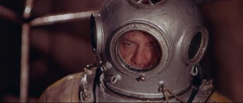 Movie still from “Krakatoa: East of Java” (1968), directed by Bernard L. Kowalski – A man wearing a diving helmet looking into a mirror; Close Up shot, High angle