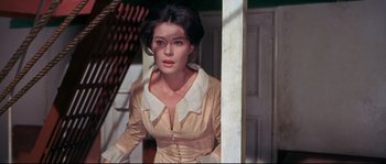 Movie still from “Krakatoa: East of Java” (1968), directed by Bernard L. Kowalski – A woman in a tan dress standing in front of a door; Close Up shot, High angle