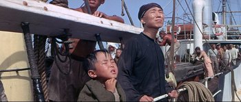 Movie still from “Krakatoa: East of Java” (1968), directed by Bernard L. Kowalski – A group of people standing next to each other on a field; Medium shot, Low angle