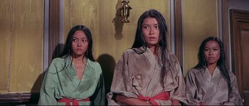 Movie still from “Krakatoa: East of Java” (1968), directed by Bernard L. Kowalski – Two young women standing next to each other in robes; Medium shot, High angle