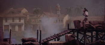 Movie still from “Krakatoa: East of Java” (1968), directed by Bernard L. Kowalski – A view of a building from across a bridge; Extreme Wide shot, High angle