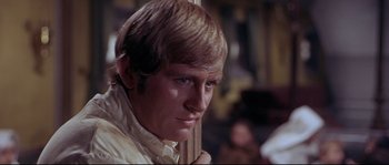 Movie still from “Krakatoa: East of Java” (1968), directed by Bernard L. Kowalski – A man with blonde hair holding a wooden stick; Close Up shot, Low angle