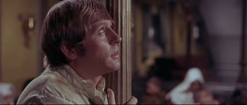 Movie still from “Krakatoa: East of Java” (1968), directed by Bernard L. Kowalski – A person leaning against a pole; Close Up shot, Low angle