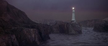 Movie still from “Krakatoa: East of Java” (1968), directed by Bernard L. Kowalski – A lighthouse is lit up at night on a rocky cliff; Extreme Wide shot, High angle
