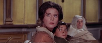 Movie still from “Krakatoa: East of Java” (1968), directed by Bernard L. Kowalski – A woman and a boy looking at the camera; Close Up shot, Low angle