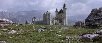 Movie still from “Krull” (1983), directed by Peter Yates – An old castle is in the middle of a grassy field; Extreme Wide shot, Low angle