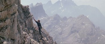 Movie still from “Krull” (1983), directed by Peter Yates – A man climbing a mountain on top of a cliff; Wide shot, Low angle
