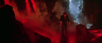 Movie still from “Krull” (1983), directed by Peter Yates – A man standing in front of a red smoke filled cave; Wide shot, High angle