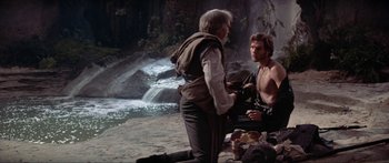 Movie still from “Krull” (1983), directed by Peter Yates – Two men are standing in front of a waterfall; Medium shot, Over the shoulder angle
