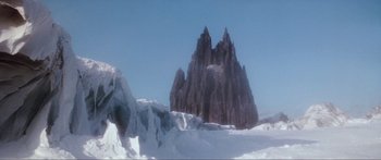Movie still from “Krull” (1983), directed by Peter Yates – A large rock formation in the middle of a snow covered field; Extreme Wide shot, Low angle