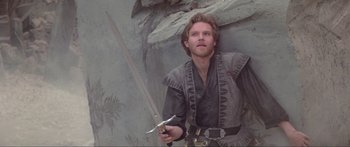 Movie still from “Krull” (1983), directed by Peter Yates – A man holding a sword in his hand; Medium shot, Low angle