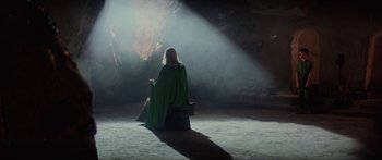Movie still from “Krull” (1983), directed by Peter Yates – A woman in a green cape sitting in a cave; Wide shot, High angle