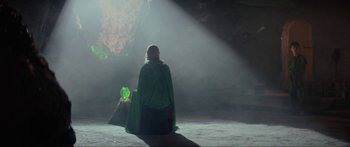 Movie still from “Krull” (1983), directed by Peter Yates – A woman in a green cape sitting on the ground; Wide shot, Over the shoulder angle