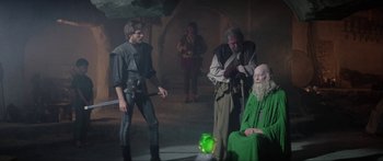 Movie still from “Krull” (1983), directed by Peter Yates – A group of people standing in a room; Wide shot, Over the shoulder angle