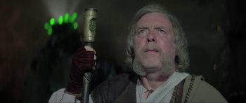 Movie still from “Krull” (1983), directed by Peter Yates – An old man with a long beard holding a stick in his hand; Close Up shot, Low angle