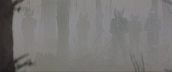 Movie still from “Krull” (1983), directed by Peter Yates – A group of people standing in the woods in the fog; Wide shot, Low angle