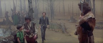 Movie still from “Krull” (1983), directed by Peter Yates – A man walking through the woods holding a sword; Wide shot, High angle