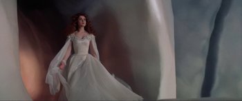 Movie still from “Krull” (1983), directed by Peter Yates – A woman in a wedding dress standing next to a wall; Wide shot, Low angle