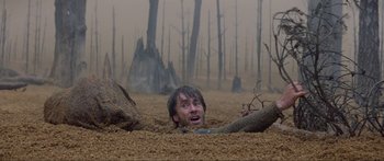 Movie still from “Krull” (1983), directed by Peter Yates – A man in the dirt looking up at the ground; Wide shot, Overhead angle