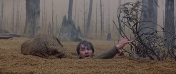 Movie still from “Krull” (1983), directed by Peter Yates – A man in the dirt with a tree in the background; Wide shot, High angle