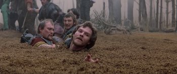 Movie still from “Krull” (1983), directed by Peter Yates – A group of people laying in the dirt; Medium shot, High angle