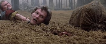 Movie still from “Krull” (1983), directed by Peter Yates – A man is buried in the ground with his head in the dirt; Close Up shot, Overhead angle