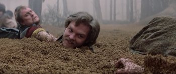 Movie still from “Krull” (1983), directed by Peter Yates – A man with long hair is laying in the dirt; Close Up shot, High angle