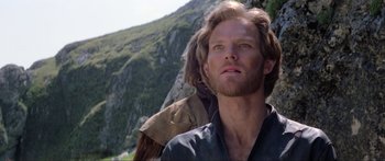 Movie still from “Krull” (1983), directed by Peter Yates – A person with a mountain in the background; Close Up shot, Low angle