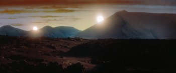 Movie still from “Krull” (1983), directed by Peter Yates – The sun is setting over a mountain range; Extreme Wide shot, High angle