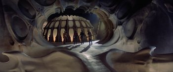 Movie still from “Krull” (1983), directed by Peter Yates – A group of people standing inside of a cave; Extreme Wide shot, Low angle