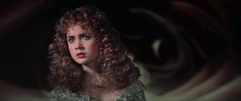 Movie still from “Krull” (1983), directed by Peter Yates – A person with curly hair wearing a dress; Close Up shot, Over the shoulder angle