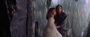 Movie still from “Krull” (1983), directed by Peter Yates – A man and a woman standing next to each other in front of a forest; Medium shot, Low angle