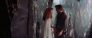 Movie still from “Krull” (1983), directed by Peter Yates – A man and a woman standing next to each other in front of a forest; Medium shot, Over the shoulder angle