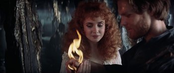 Movie still from “Krull” (1983), directed by Peter Yates – A woman with red curly hair is holding a flame; Close Up shot, Over the shoulder angle